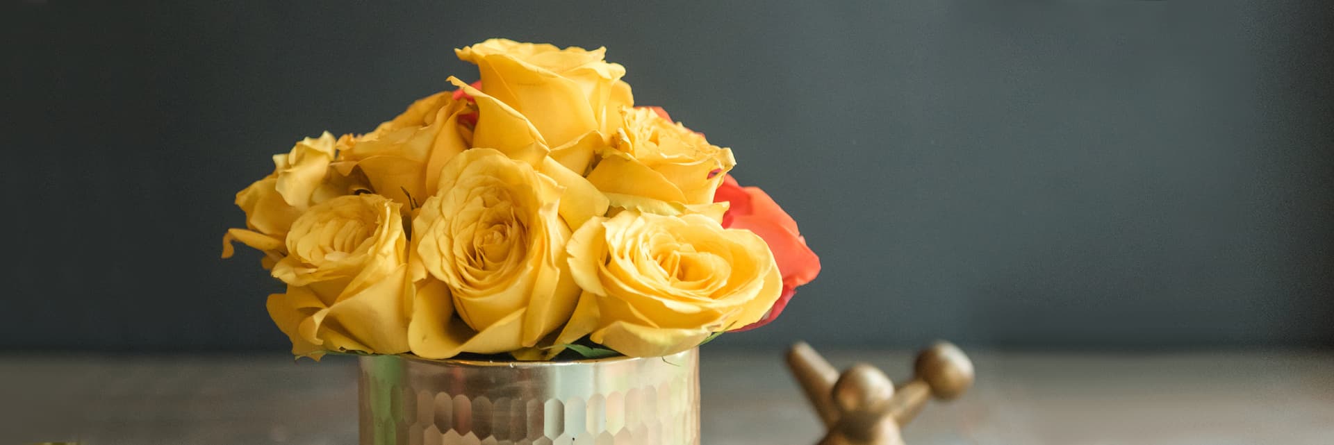 Vibrant yellow roses elegantly arranged in a stylish metallic vase, ideal for any occasion.
