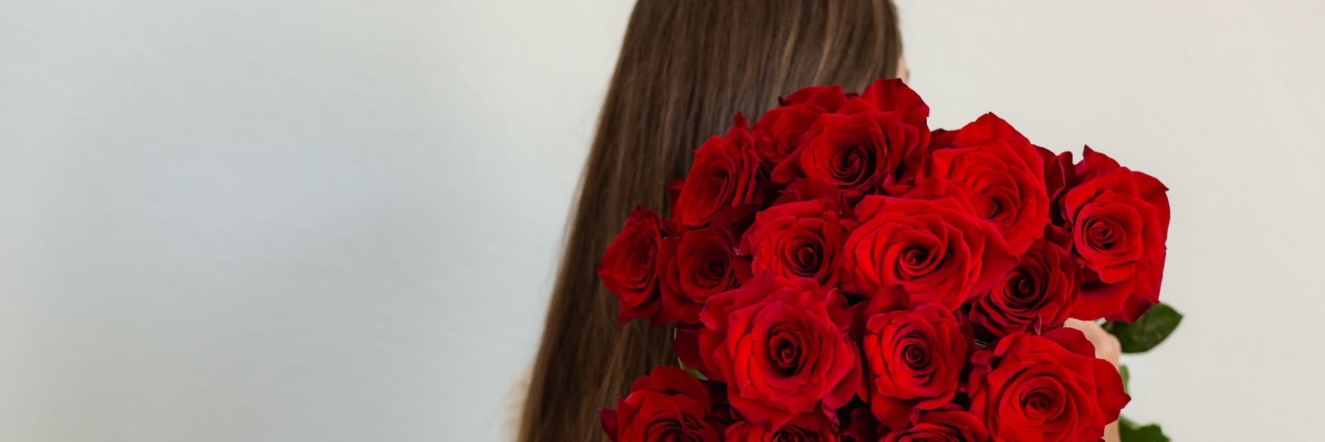 A woman holding a stunning bouquet of bright red roses, ideal for special moments.