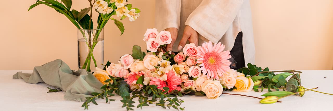 A vibrant floral arrangement with pink roses, gerbera daisies, and lush greenery.